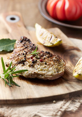 Grilled pork steak with fresh rosemary on wooden background. 