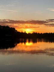 Fototapeta premium Magic august summer sunset at forest lake with sunlight reflected on water surface