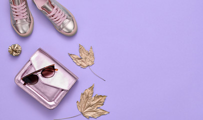Autumn fashionable Outfit, Maple Leaf. Woman Accessories Set. Minimal Creative autumnal Flat lay on purple. Fashion shoes, Trendy gold Handbag, Glamour Sunglasses. Fall color.
