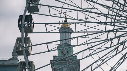 Ferris wheel on background white sky and historic building. Cloudy winter weather