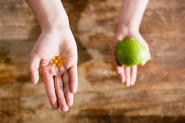 cropped view of woman holding apple and food additives in capsules