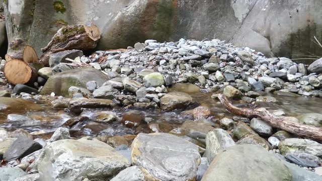 Small Creek In The Mountains. Fast water stream at the front of old rocks.Natural background.