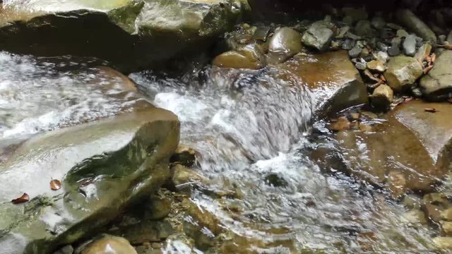 Small Creek In The Mountains. Fast water stream flow between old rocks.Natural background.