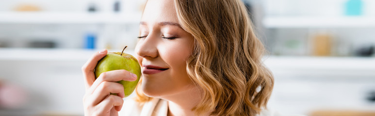 panoramic crop of woman with closed eyes smelling apple