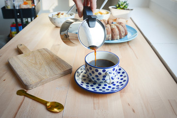 Coffee preparing in moka pot. Italian moka kettle. Brewing coffee at home. Woman hands. Woman preparing coffee in traditional Italian moka pot. Wooden table.
