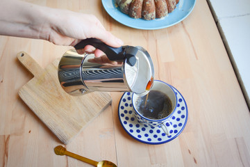 Coffee preparing in moka pot. Italian moka kettle. Brewing coffee at home. Woman hands. Woman preparing coffee in traditional Italian moka pot. Wooden table.