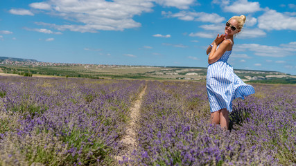Joyful lady on a lavender field with charismatic appearance sunglasses stands smiling stands