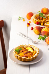 Open pie from shortcrust pastry with peaches, peach clafoutis on white table