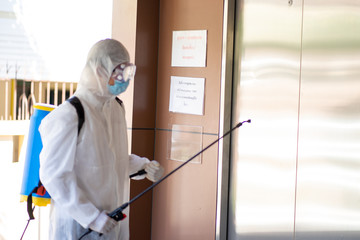 health care social worker in protective white jumpsuit with glasses and surgical face mask using...