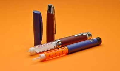 two insulin pens, injector pens on an orange background. for insulin therapy. selective focus.
