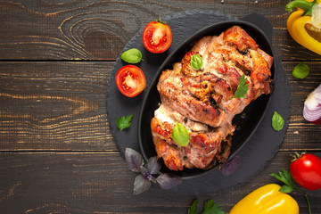 Baked pork ham on a wooden background, fried piece of meat with spices, fresh vegetables, top view