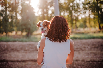 young happy woman in a car cuddling her cute dog. Travel concept