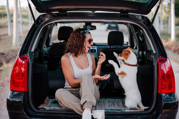young happy woman in a car enjoying with her cute dog. Travel concept