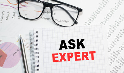 Business concept. Notebook with text ASK THE EXPERT sheet of white paper for notes, calculator, glasses, pencil, pen, in the white background
