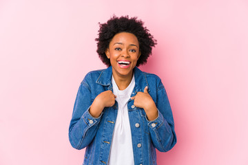 Young african american woman against a pink backgroound isolated surprised pointing with finger, smiling broadly.