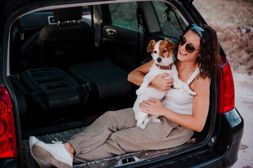 young happy woman in a car enjoying with her cute dog. Travel concept