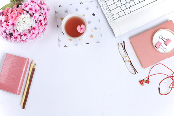 Work desk of a modern woman, home office. Notepad, tea, spring flowers on a light table. Minimal business concept, flat lay,