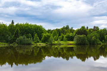 Fototapeta na wymiar View of a forest lake, which reflects a beautiful green forest