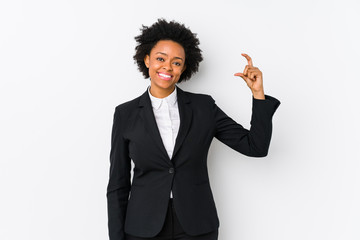 Middle aged african american business  woman against a white background isolated holding something little with forefingers, smiling and confident.