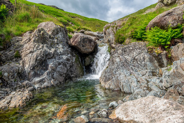 Fototapeta na wymiar Over Beck Waterfall on a summers afternoon at the foot of the path to Yewbarrow Mountain, Lake District National Park, Cumbria, England, UK.