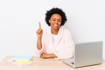 Middle aged african american woman working at home isolated showing number one with finger.