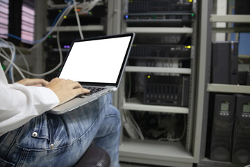 Technician using laptop while analyzing server in data center.
