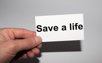 Message on the card SAVE A LIFE, in hands of businessman.