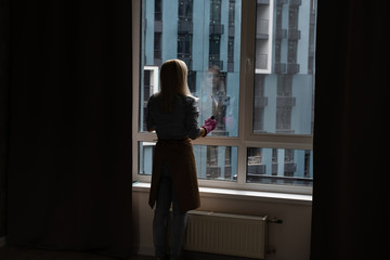 Smiling black woman cleaning windows with glass cleaner