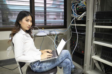 Technician using laptop while analyzing server in data center.