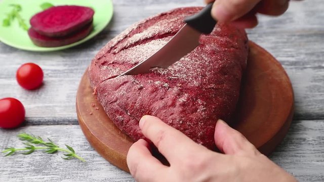 Red beet bread is cut with a knife. Side view, close up.