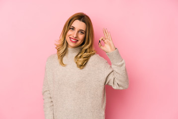 Young blonde cute woman wearing a sweater isolated cheerful and confident showing ok gesture.