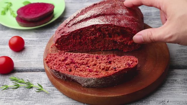 male hand take piece of red beet bread. Side view, close up.