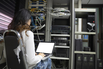 Technician using laptop while analyzing server in server room