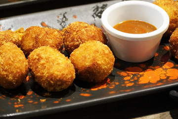 Typical Spanish croquettes with deep mustard and ketchup on a black plate