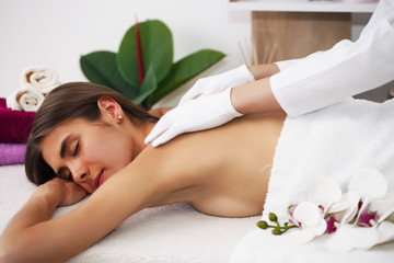 Obraz na płótnie Canvas Beautiful woman getting massage in spa, brunette lying resting.