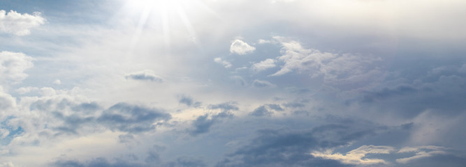 Naklejka na ściany i meble Panorama of the sky with gray clouds illuminated by the sun