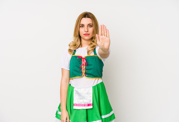 Young woman wearing a saint patricks day clothes isolated standing with outstretched hand showing stop sign, preventing you.