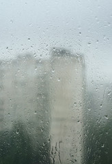 Blurred buildings through a glass covered with drops of water.