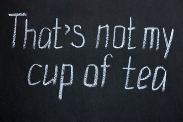 Fototapeta premium Chalk writing on a dark board This is not my cup of tea. A wise phrase