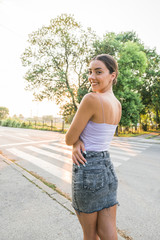 Fototapeta premium Portrait of beautiful caucasian woman smiling looking away at park during sunset. Outdoor portrait of a smiling young girl. Happy cheerful girl laughing on the street