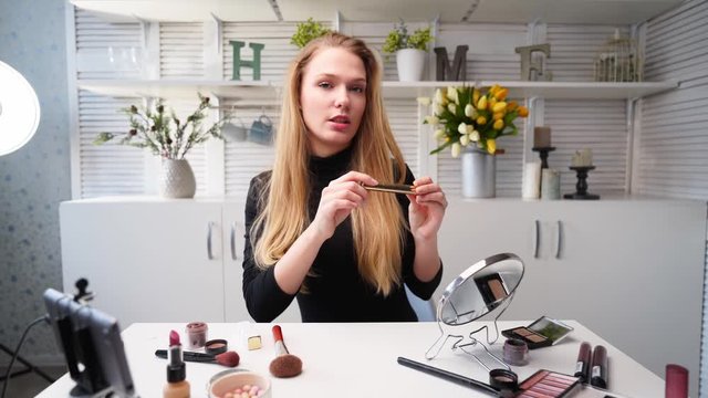 Beauty blogger woman filming daily makeup routine tutorial on camera. Influencer blonde lady live streaming eyelashes mascasra review in home studio with professional lighting equipment. Vlogger job.