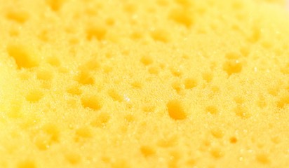 Close-up of a yellow washcloth for bathing in a bath or shower. The structure and texture of the spongy material with holes.