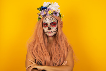 Waist up portrait of beautiful young female with positive expression, has crossed arms, feels happy and confident, wears casual clothes, isolated over gray background