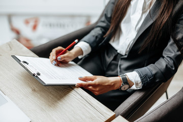 Young girl office worker or business lady signs documents. Concentrated businesswoman working with papers. Business concept