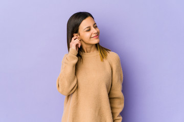 Young woman isolated on purple background covering ears with fingers, stressed and desperate by a loudly ambient.