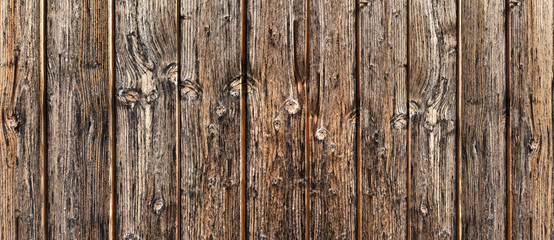 Alte rustikale, stark verwitterte braune Holzwand aus vertikalen Brettern in Nahaufnahme