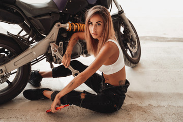 Fototapeta na wymiar Hot looking girl with wrenches posing with a sport motorcycle