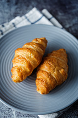 Fresh croissants on a plate with cups of coffee
