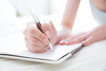 ノートにメモする女性の手元