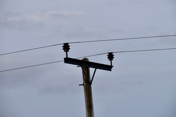 wooden electric pole with two wires and grey clouds in the background